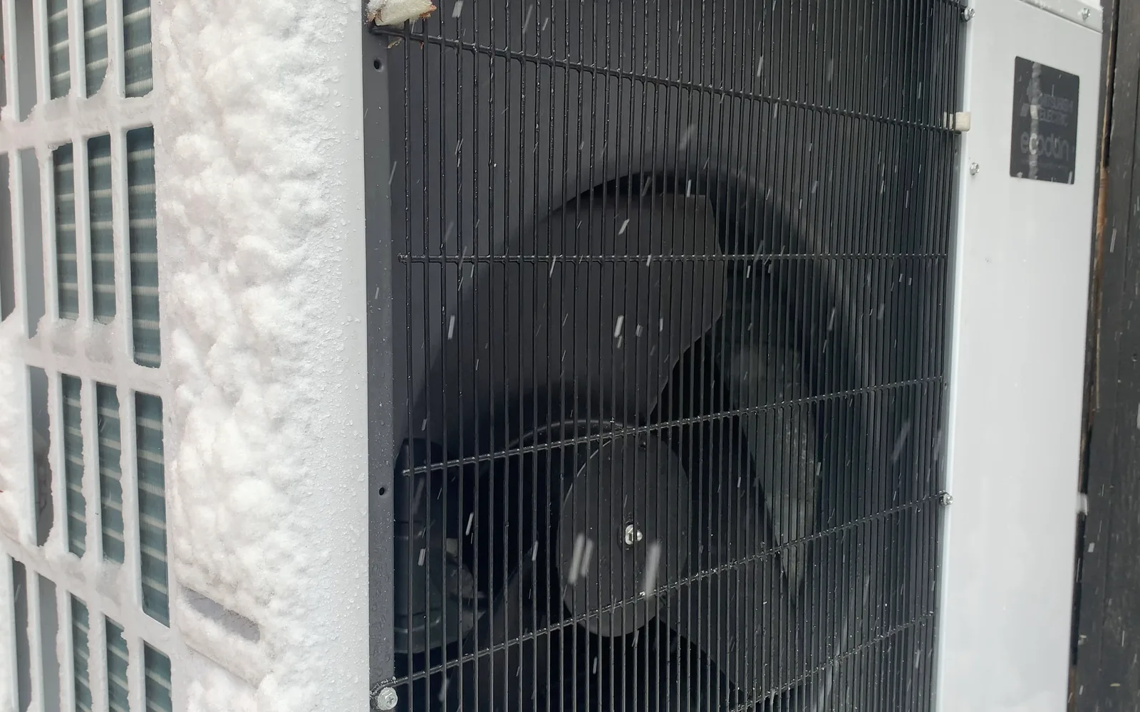 Licensed photo: outdoor heat pump unit in snow beside a home
